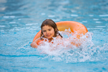 Child play in pool on inflatable ring. Kid with inflatable ring in swimming pool. Child water toys. Children play in tropical resort. Child playing in swimming pool. Summer vacation concept.