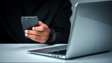 Business male holding smartphone, checking messages, on desk, having laptop, business concept