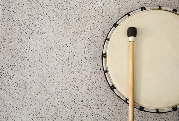 Drum and drumstick on grey table, top view with space for text. Percussion musical instrument