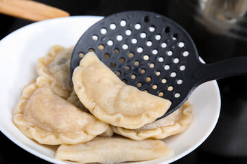 Putting delicious dumplings (varenyky) on plate, closeup