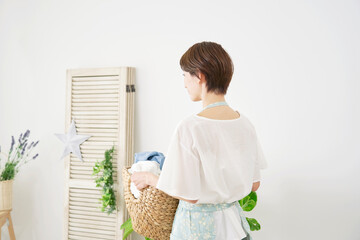 家で洗濯物を運ぶ女性