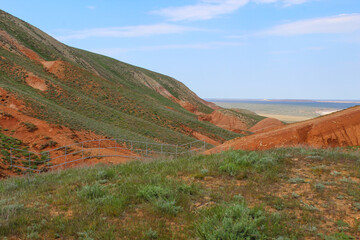 Fototapeta premium View of the bright red sandy-clayey slopes of the mountain Big Bogdo