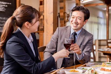 居酒屋で女性の部下と飲み会・宴会をする仕事仲間・上司の男性
