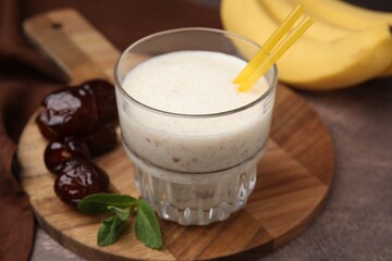 Glass of delicious date smoothie, mint and dried fruits on brown table, closeup