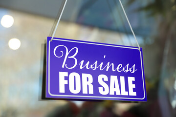 Blue sign with Business For Sale hanging on glass door
