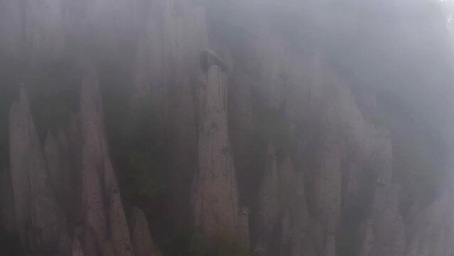 Aerial view around the Earth Pyramids of Ritten pillars, in foggy Dolomites, Italy