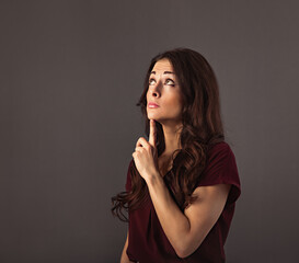Fototapeta premium Beautiful thinking fun grimacing business woman have an strategy idea looking up on grey studio background with empty copy space for text. Closeup