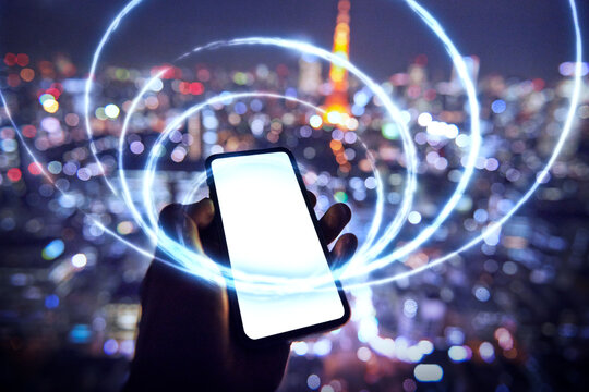 東京を背景にスマートフォンを持つ人