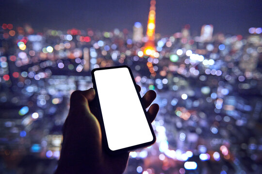 東京を背景にスマートフォンを持つ人