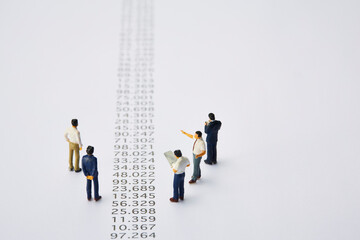 羅列された数字とミニチュアの人々