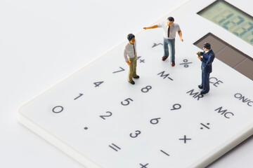 電卓の上に立つミニチュアの人