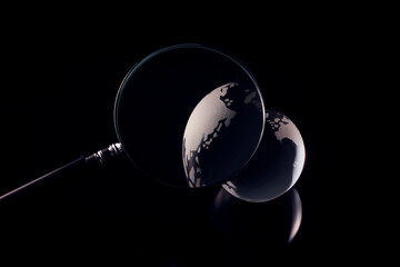 暗闇のガラス製の地球を拡大する虫眼鏡