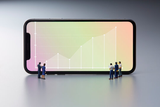 スマートフォンに表示されたグラフとミニチュア人形