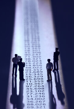 複数の並んだ数字を見るスーツを着た人のミニチュア