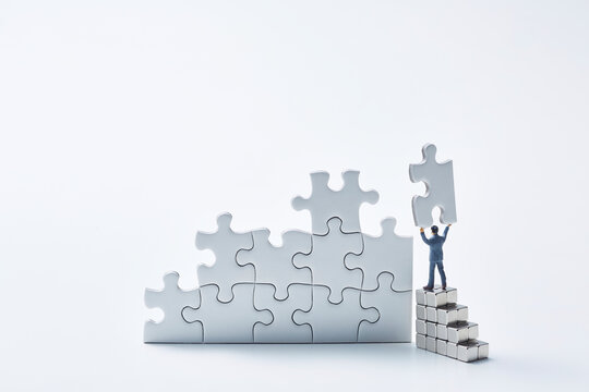 白いパズルを組み立てる1体のミニチュア人形