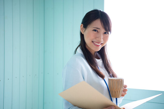 ファイルを開いてカップを持っている女性