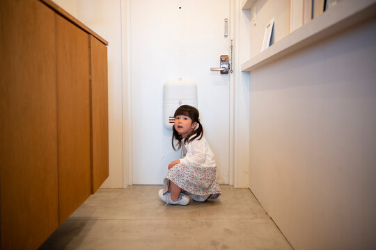 母親の靴を履いて玄関にいる女の子