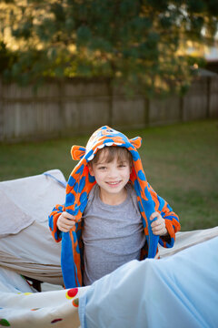 シーツで作ったテントから出て立っている男の子