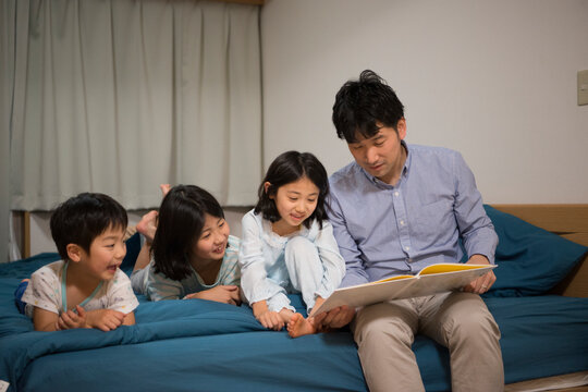 パジャマで絵本を読んでいる子供と父親