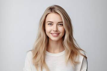 Fototapeta premium Headshot of a beautiful blond smiling young woman looking at the camera on gray background. Generative AI