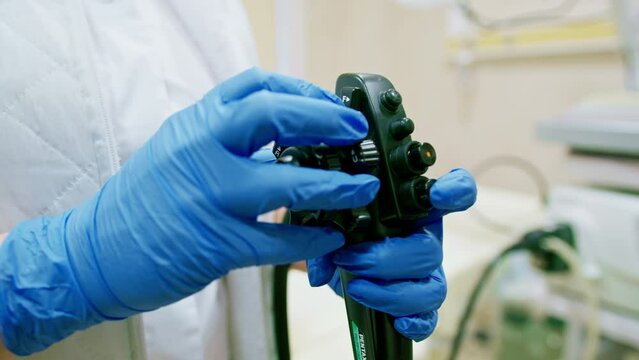 Close-up of doctor's gloved hand with endoscope during diagnostic gastroscopy or colonoscopy in clinic