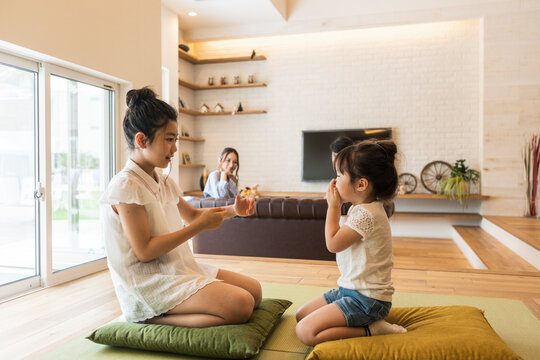和室で遊ぶ姉妹と見守る両親