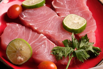 Fish filet is fish meat that has been cut or sliced away from the bone by cutting lengthwise along one side of the fish. on a brown wooden cutting board. cherry tomato, lime. Istiompax indica. Marlin
