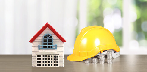 Yellow hardhat model house and coin with trading graph