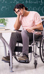 Fototapeta premium Young handsome man in wheelchair in front of chalkboard