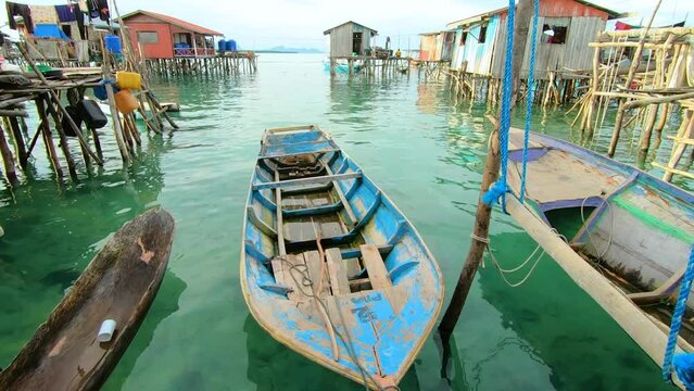 Close shot of a boat floating near water houses and sea in the background at Pulau Omadal in Semporna, Sabah Malaysia.