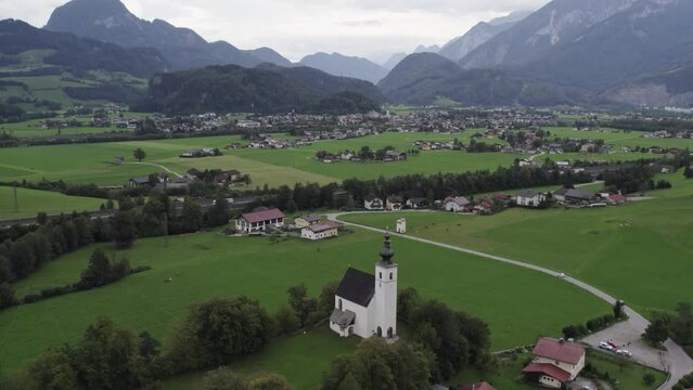 Drone flies over the Wallfahrtskirche St. Nikolaus Golling (Austria) mountain backdrop, aerial