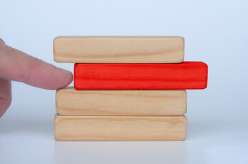 Hand pushing red wooden block from other stacked wooden block. Customizable space for text. Copy space.