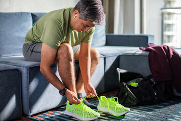 Middle aged man tying his shoelaces and getting ready to go workout