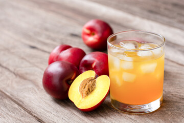 Glass of peach juice and fresh ripe peach fruit on wooden table background.