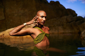 Non-binary person of color poses in water, shows jewelry inside scenic creek at night. Lgbtq ethnic...