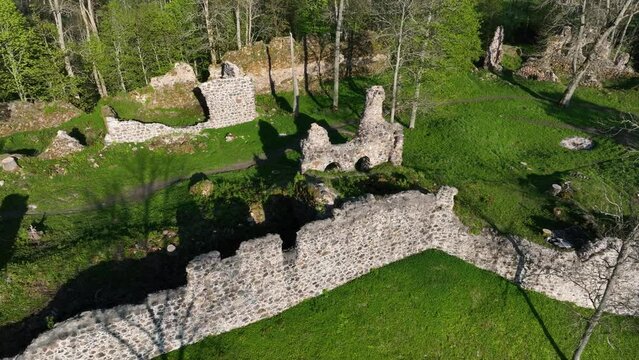 Approaching aerial view of Helme Order Castle with strong shadows on a sunny evening. Estonia.