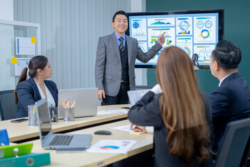 Office Conference Room Meeting Presentation: asian Businessman Talks, Uses Wall TV to Show Company Growth with Big Data Analysis, Graphs, Charts, Infographics. Multi-Ethnic e-Commerce Startup 
