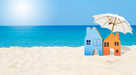 Miniature wooden house with white umbrella on tropical sandy beach with space on blue sea...