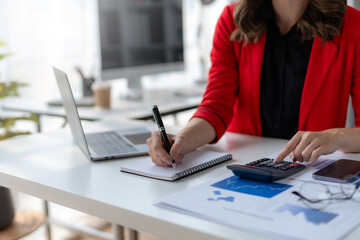 Close-up of businesswoman hands using a calculator to check company finances and earnings and budget. Business woman calculating monthly expenses, managing budget,  papers, loan documents, invoices.