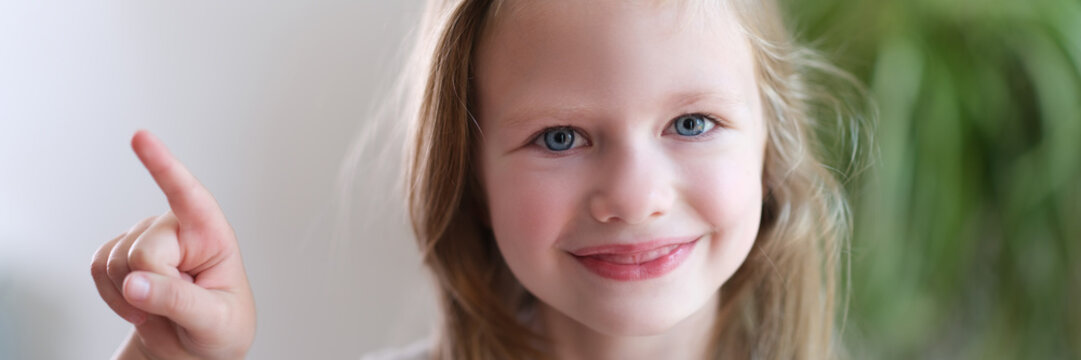 Portrait of cheerful smiling child girl points finger to side. direction indication advertising banner