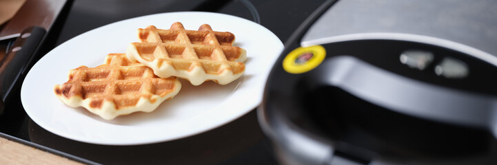 Delicious fresh sweet cooking waffles on plate in kitchen. Belgian waffle recipe concept