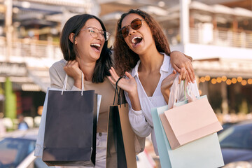 Happy, women friends with shopping bags and at street in city with a smile. Promotion or discount, happiness or retail and excited or cheerful female people shop together for fashion products