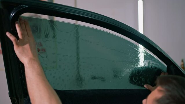 Male car service worker glue window tinting in luxury car detailing car repair the concept of love for cars and a protection