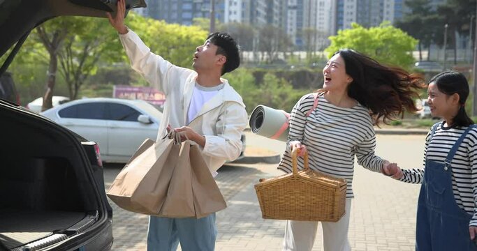 자동차를 주차하고 피크닉바구니를 꺼내는 가족