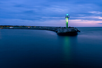 Fototapeta premium Stone pier in Darłowo in the evening. Lights on the beach. Traffic lights in the port. Blue hour. Poland