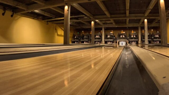 Bowling ball rolling down the alley and striking pins - low angle view