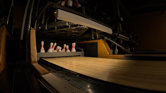 Behind the scenes of a bowling alley as the sweep knocks the pins in the pit