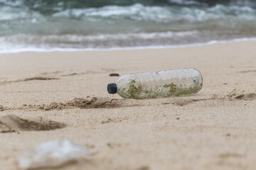 Plastic trash at the sandy beach. Plastic pollution concept. Single-use plastic is a human addiction that is destroying our planet and impacts our waters, sea life and humans.