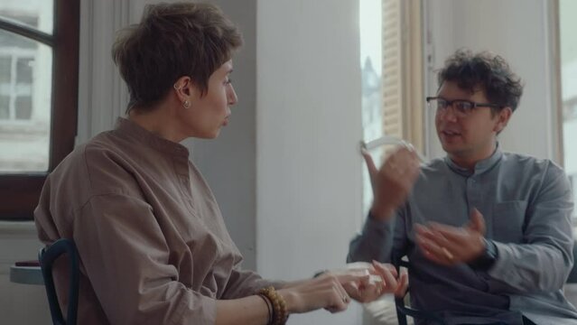 Young frustrated family couple fighting during counseling session, blaming each other, getting angry and upset in psychologist office