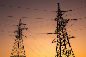 High-voltage power lines at sunset. Electricity distribution station. Electricity pylons on the background of the sky.
